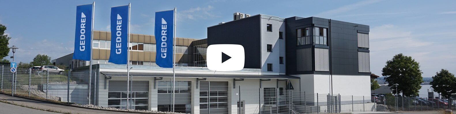 Gedore Automotive company building with flags in the foreground with play button.