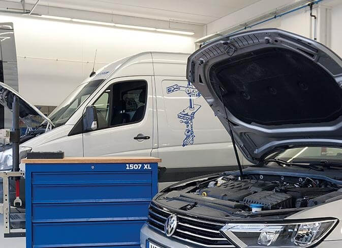 Photo with a van, a workshop trolly and a car in the workshop.